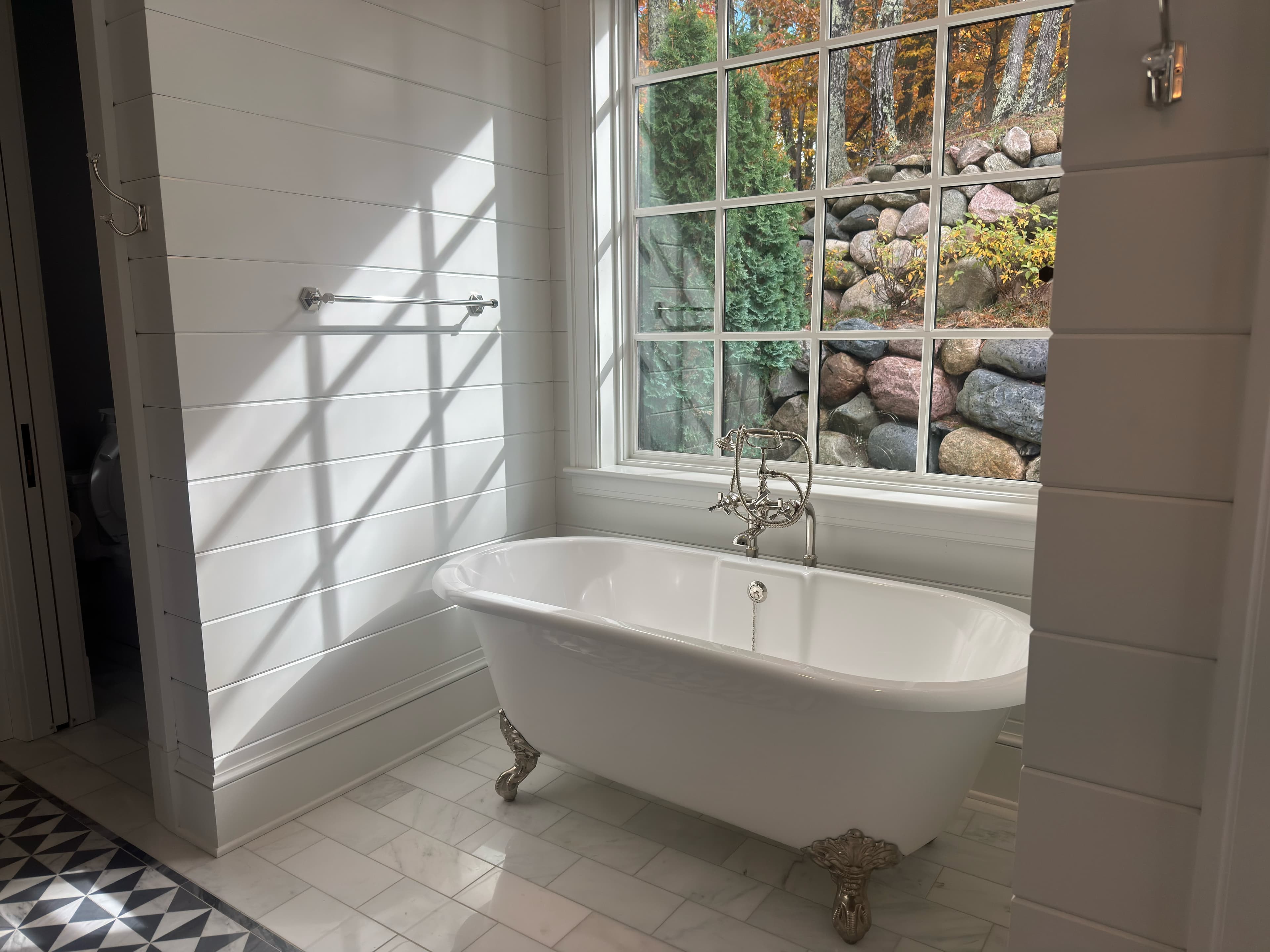 A clawfoot tub under a sunny window, the bathroom freshly cleaned