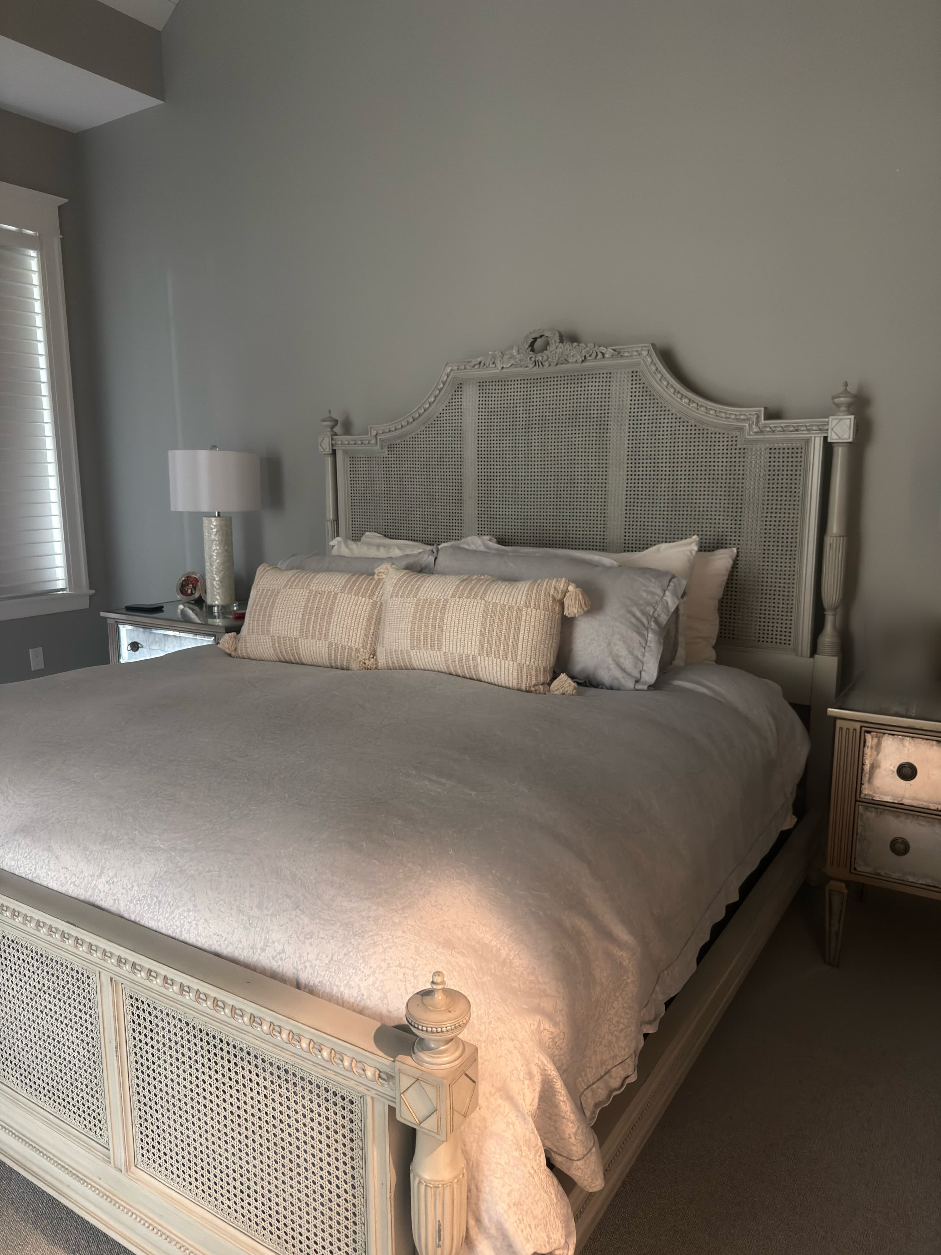A bedroom with a freshly made bed and a cane headboard