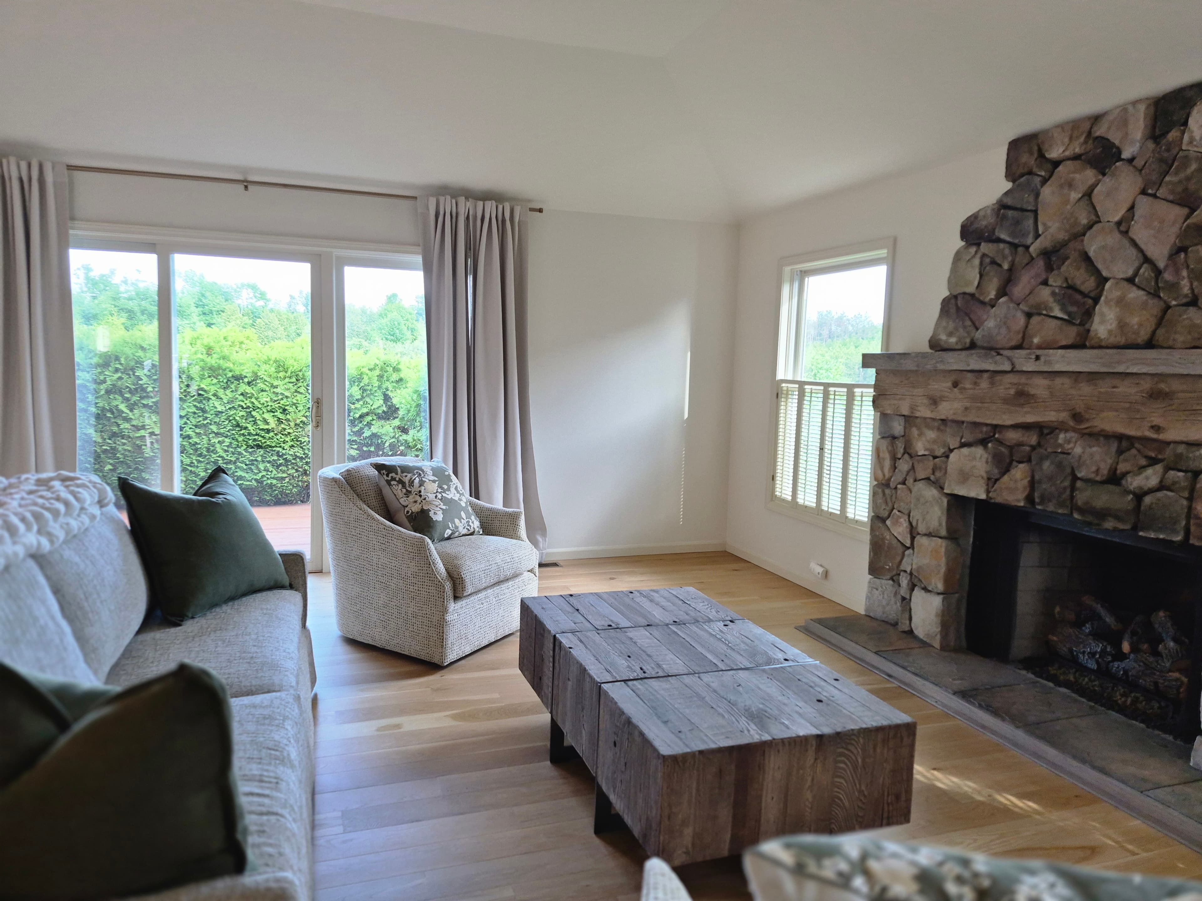 A sunny living room with a stone fireplace, freshly cleaned